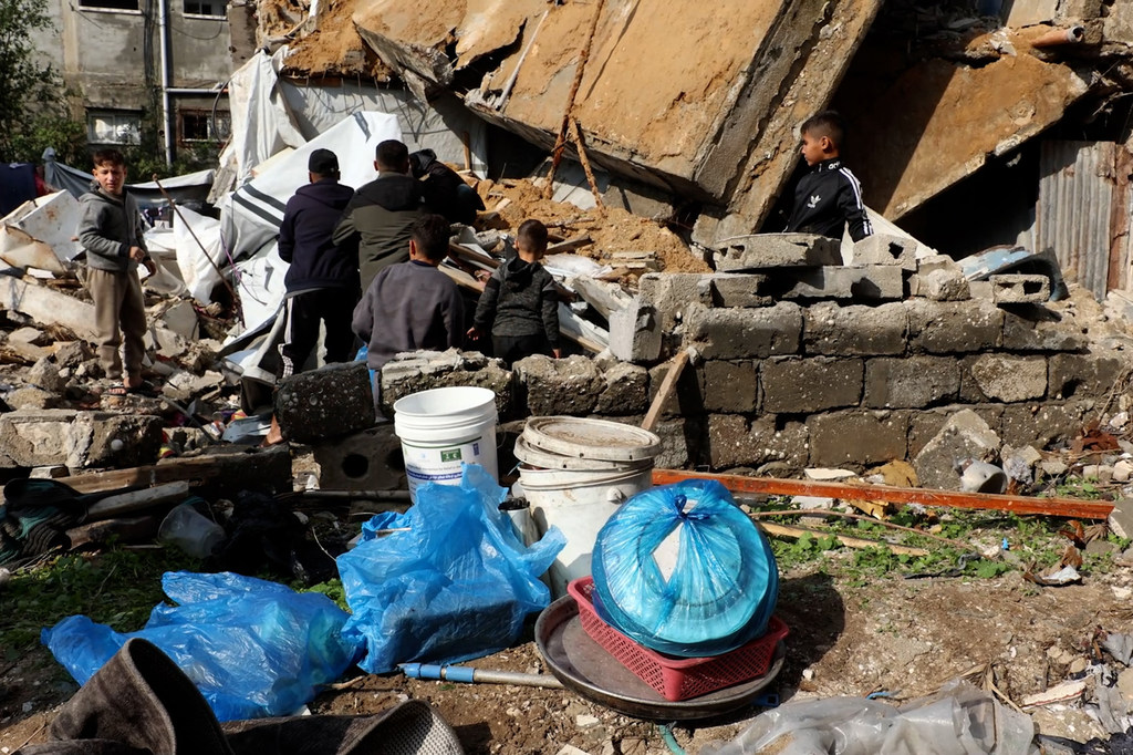 Des enfants et des adultes dans les décombres de bâtiments effondrés à Gaza.